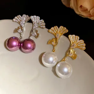 Close-up detail of elegant ginkgo leaf dangle earrings with pearls and zircons