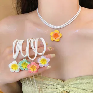 Gros plan de colliers de fleurs de frangipanier en résine avec cordons blancs double couche.