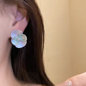 Detail shot of elegant silver flower stud earring with pearl on ear