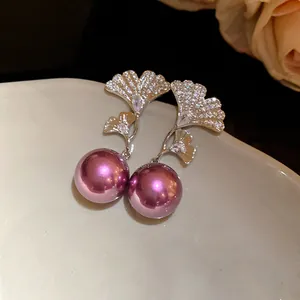 Detail of silver needle earrings with zircon fan leaves and purple metallic pearls