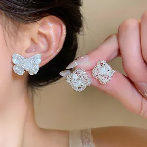 Detailed view of elegant silver needle hollow lace diamond and butterfly stud earrings