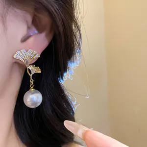 Close-up of elegant 18K gold ginkgo leaf earrings with pearls and zircons