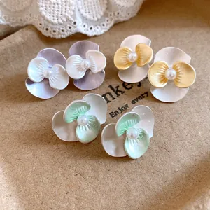 Close-up detail of vintage oil-drop pearl flower stud earrings in multiple colors.