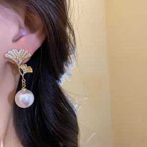 Detailed close-up of elegant 18K gold plated ginkgo leaf drop earrings with white pearls