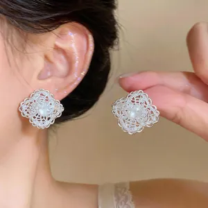 Close-up detail of hollow silver lace diamond stud earrings with sparkling zircon center