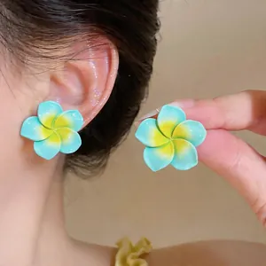 Gros plan détaillé de boucles d'oreilles en forme de fleur en résine bleu et jaune.