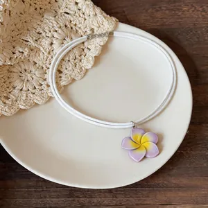 Vue détaillée d'un collier ras-du-cou blanc à double couche avec fleur en résine violette