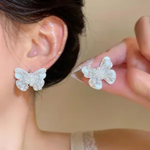 Detail shot of elegant white shell butterfly earrings with pearl and zircon accents