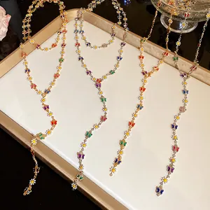 Detail of colorful enamel butterfly and daisy charms on a dainty gold Y-necklace