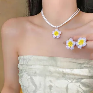 Gros plan élégant du collier et des boucles d'oreilles frangipanier en résine sur mannequin