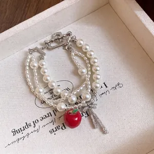 Pulsera de perlas multicapa con lazo de circón, colgante de manzana roja y cierre OT.