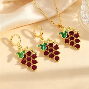 Primer plano detallado de un conjunto de joyas de uva dorada con piedras púrpuras.