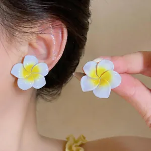 Vue détaillée de boucles d'oreilles élégantes en résine fleurs de frangipanier blanches