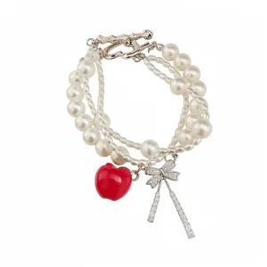 Elegante pulsera de perlas multicapa con dije de manzana roja y lazo de circonita