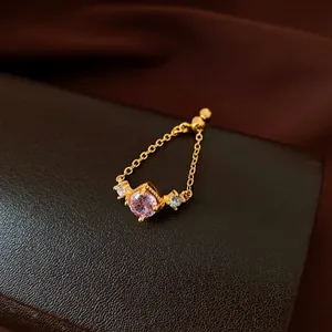 Macro view of an elegant gold chain ring featuring a pink central zircon gemstone.