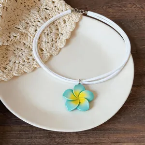 Vue détaillée du pendentif fleur en résine bleue et jaune sur un collier blanc