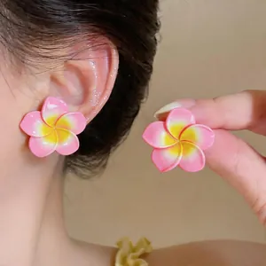 Vue détaillée de boucles d'oreilles fleur en résine rose avec dégradé jaune sur l'oreille
