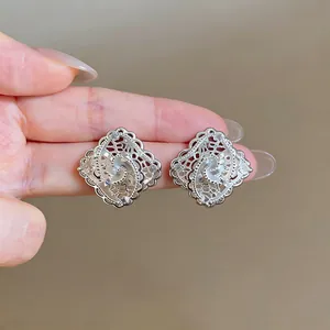 Detailed view of hollow silver lace rhombic stud earrings with sparkling zircons.
