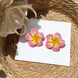 Vue détaillée de haute qualité des boucles d'oreilles frangipanier en résine rose et jaune.