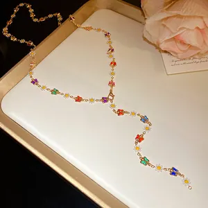 Detailed view of gold-tone Y-necklace featuring colorful enamel butterflies and daisies.