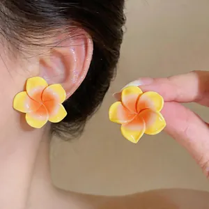 Détail de boucles d'oreilles fleurs en résine jaune avec un dégradé orange vif au centre