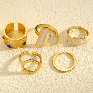 Detailed view of five vintage gold open rings with irregular textures and white enamel.