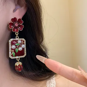 Close-up view of vintage dark red flower pendant earrings with pearls and sparkling crystals