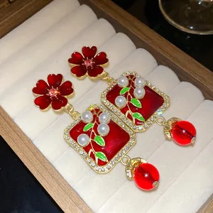 Close-up detail of vintage red flower drop earrings with pearls and crystal accents