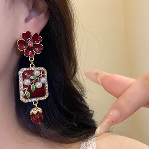 Detailed shot of vintage dark red enamel flower earrings with pearls worn on ear