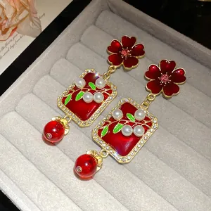 Detailed view of vintage red flower earrings with pearls and crystals in a grey box