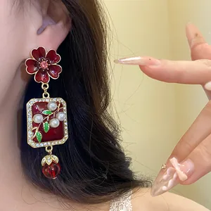 Detail view of red flower earrings with pearls and crystal-encrusted enamel charms.