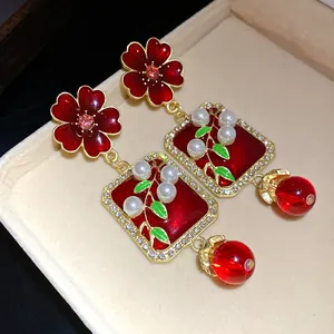 Detailed view of vintage palace style red enamel flower earrings with pearls and crystals.