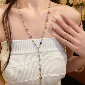Detail view of colorful enamel butterfly and flower charms on a long silver Y-chain necklace.