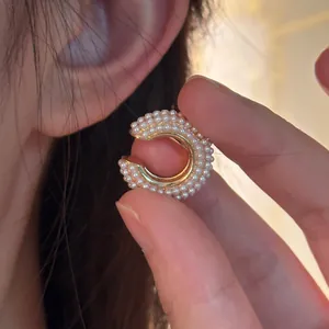 Close-up of elegant C-shaped ear cuff densely set with small white pearls for non-pierced ears.
