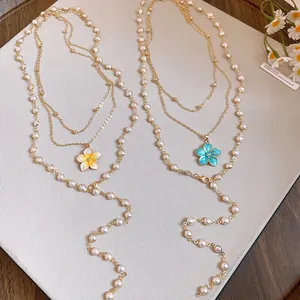 Detail of layered pearl beaded necklaces with yellow and blue enamel flower charms