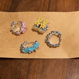 Detail view of sweet enamel flower hoop earrings in multiple colors on kraft paper.
