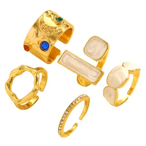 Vintage gold-tone ring set featuring irregular textures and white enamel reliefs.