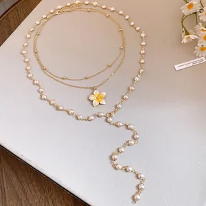Detailed view of layered pearl and enamel flower necklace in elegant gold finish