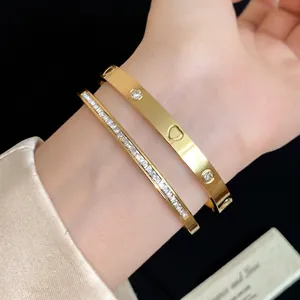 Elegant gold stainless steel bangles set with zirconia and unique heart cutout detail.