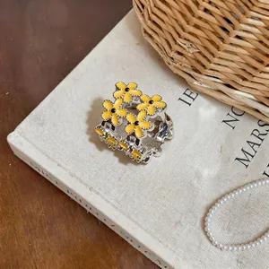 Close-up of sweet yellow enamel flower ear cuff with delicate zircon details on a book.