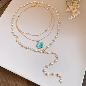 Detailed view of layered gold necklace with elegant blue flower pendant and pearls