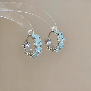 Detailed macro shot of light blue enamel flower hoop earrings in silver finish