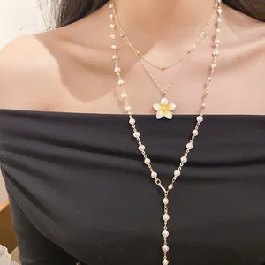 Detail showing multi-layer pearl necklace with yellow enamel flower pendant on model