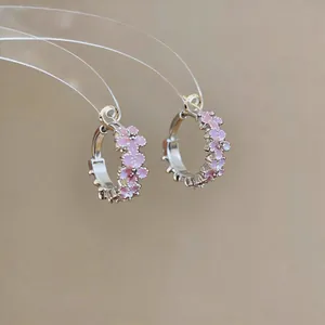Close-up detail of elegant silver hoop earrings decorated with pink enamel flowers and zircons