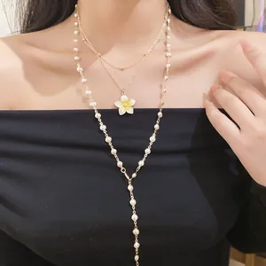 Close-up of layered pearl beaded necklace set with a delicate yellow flower pendant.