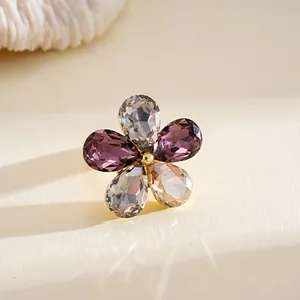 Close-up view of flower-shaped ring featuring colorful pear-cut crystals and gold band.