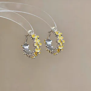 Detailed view of yellow floral hoop earrings with elegant enamel finish and silver base.