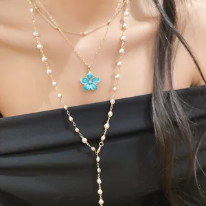 Close-up of elegant layered gold necklace set with blue enamel flower and pearl beads