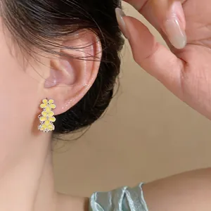 Close-up view of elegant yellow floral hoop earrings with zircon accents worn on model ear