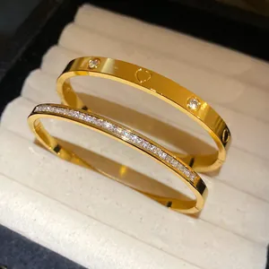 Close-up of gold stainless steel bangles with heart cutouts and pavé zircon stones